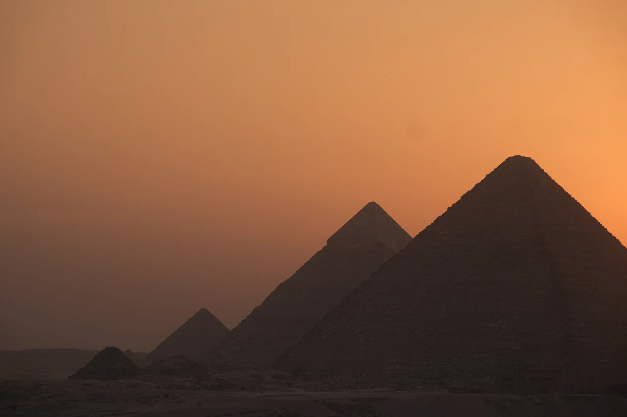 Majestic view of the Great Pyramids of Giza at golden hour with clear blue sky and desert landscape